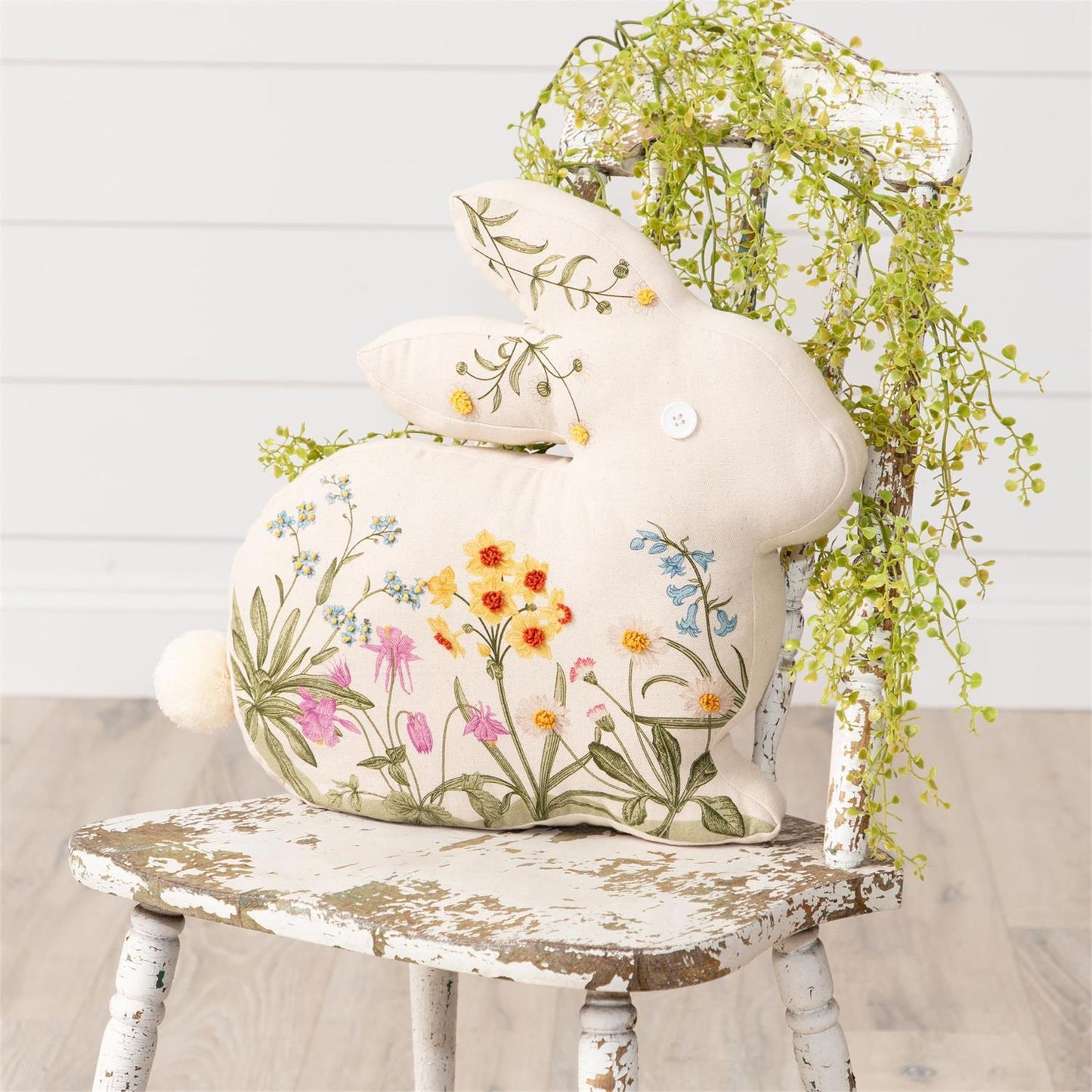 Rabbit shaped embroidered floral pillow in cotton cream fabric with spring flowers embroidered on front with button eye and fluffy tail.