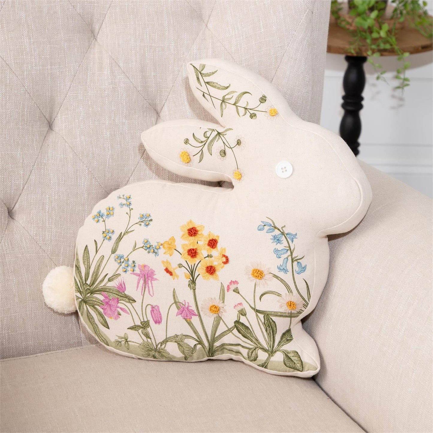 Rabbit shaped embroidered floral pillow in cotton cream fabric with spring flowers embroidered on front with button eye and fluffy tail.