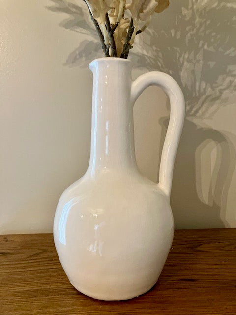 Close up of white ceramic long neck pitcher.