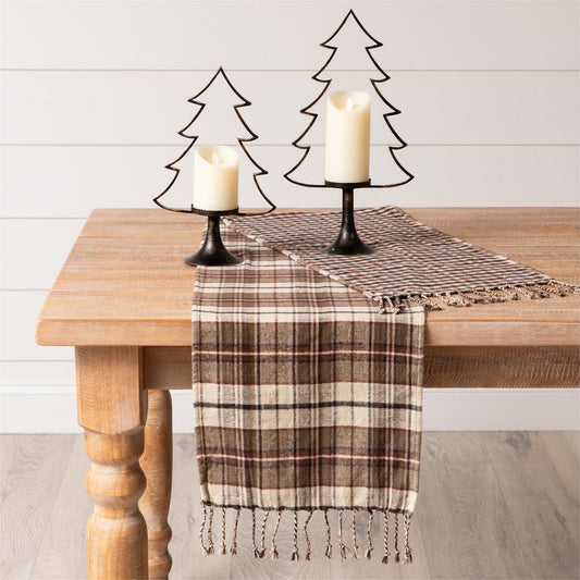 Brown white and black plaid table runner with checkered pattern on back in same colors. Has tassels on ends. 