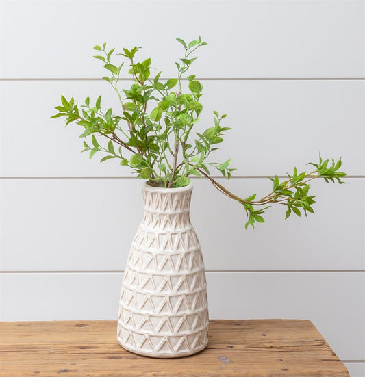 Cream vase with reactive glaze finish. This ceramic vase has a debossed triangle design.